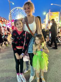 Woman with two young daughters at a carnival.
