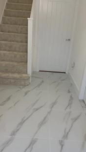 Hallway with new marble-look flooring and carpeted stairs.