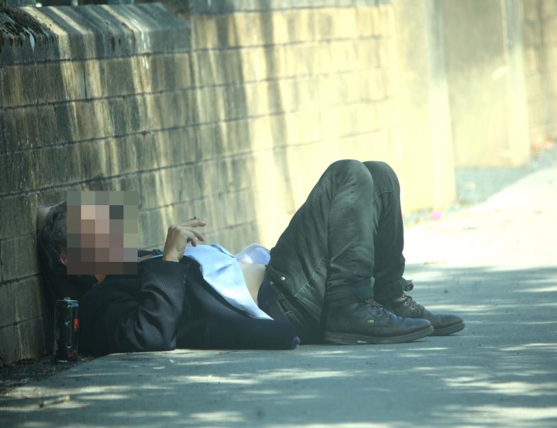 Man lying on the ground next to a wall.