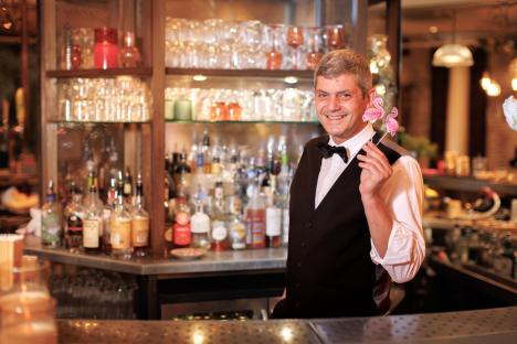 Bartender holding flamingo cocktail picks behind a bar.