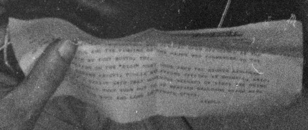 Grainy black and white photo of a damaged document with illegible text.