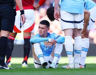 Phil Foden of Manchester City sitting on the field injured.