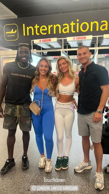 Four people posing for a photo at an airport in London.
