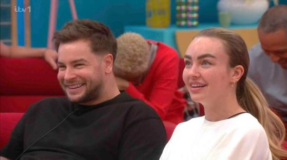 Two people smiling and looking at something off-camera.