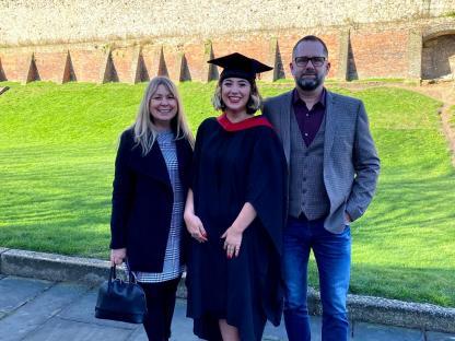 Krystal in cap and gown with parents Sharon and Dave Simes