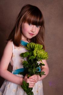 Girl in white dress holding green flowers.