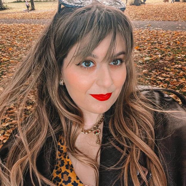 Mollie Quirk in an outdoor selfie, with a background of fallen leaves.