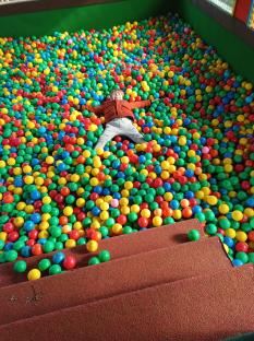 Child lying in a ball pit.