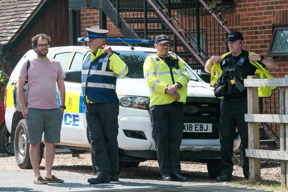 Three police officers and a man standing by a police car.