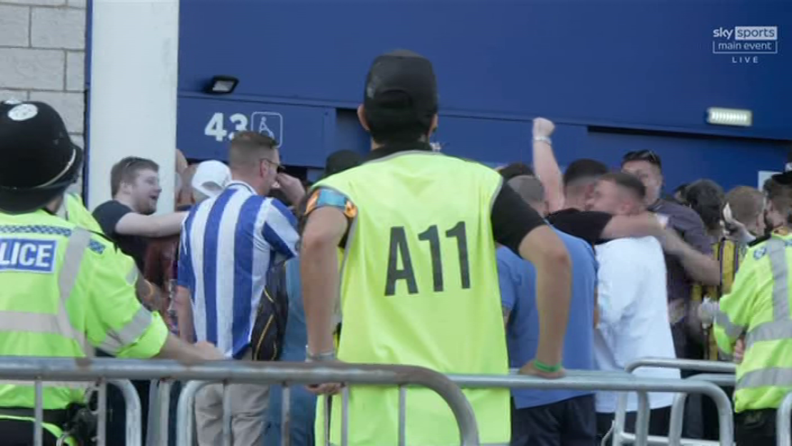 Police officers and security personnel standing near a group of jubilant fans.