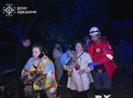 Emergency personnel evacuating residents and their dogs from a damaged building.