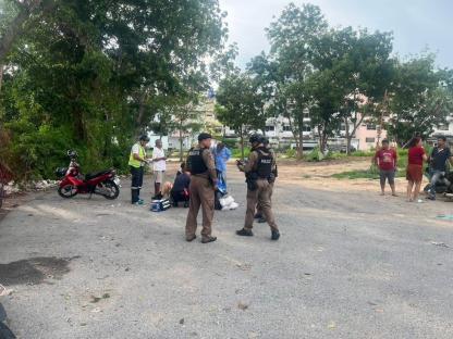 Police officers attending to an injured man in a parking lot.