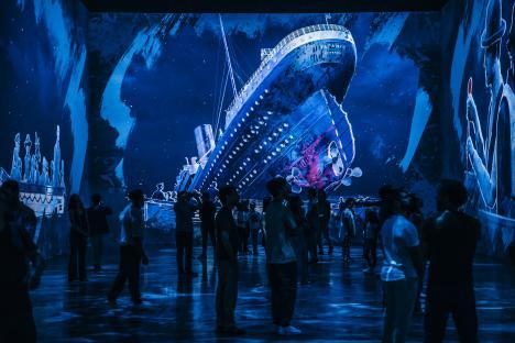 People viewing a large-scale projection of the Titanic sinking.