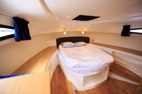 Boat cabin with bed and wood flooring.