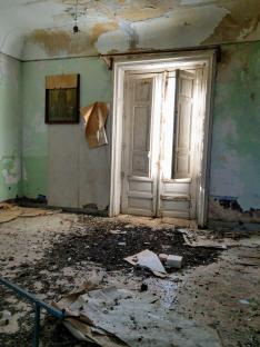 Damaged room with debris on the floor and a partially open door.