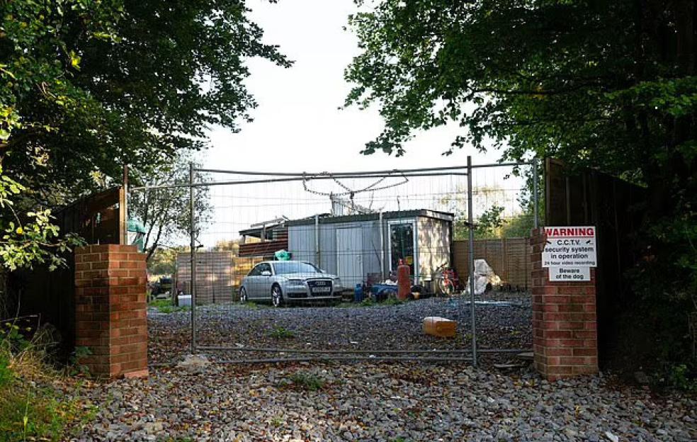 a car is parked in front of a fence with a warning sign on it