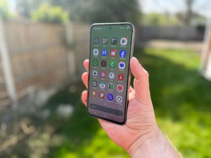 Hand holding smartphone displaying various app icons.