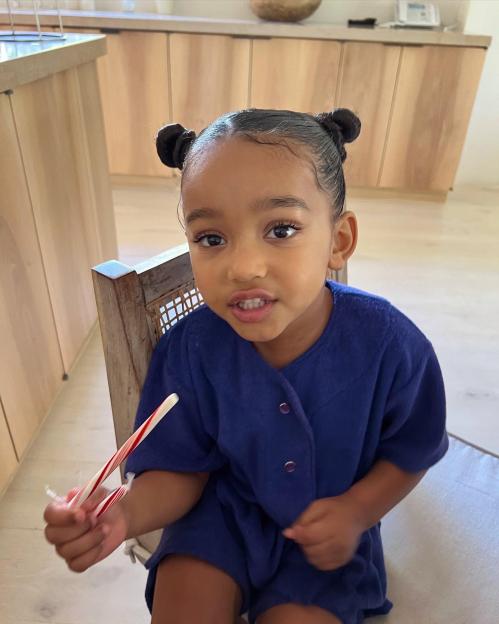 Chicago West, a young child, wearing a navy blue outfit and holding two candy canes.