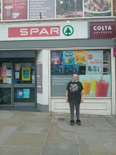 Woman standing in front of a SPAR store.