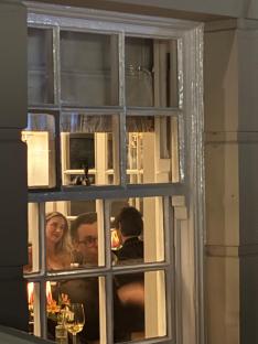 Zara McDermott and Louis Tomlinson seen through a window at a restaurant.
