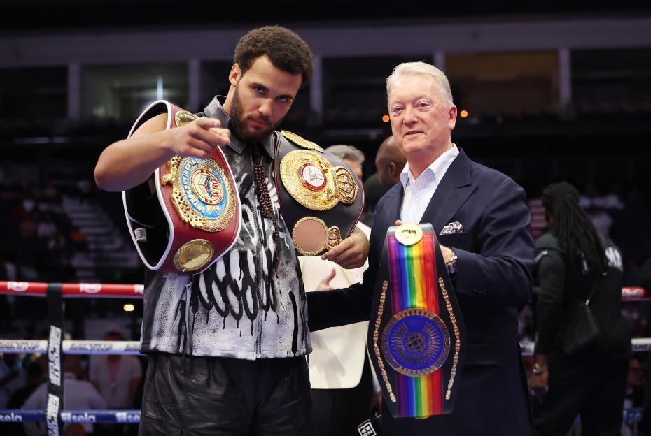 Moses Itauma posing with boxing championship belts.