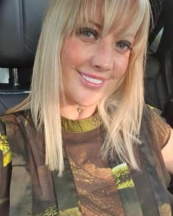 Woman with blonde hair smiling in a car.