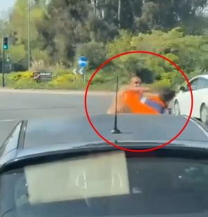 Video still of a road rage incident: two men fighting on a roundabout.