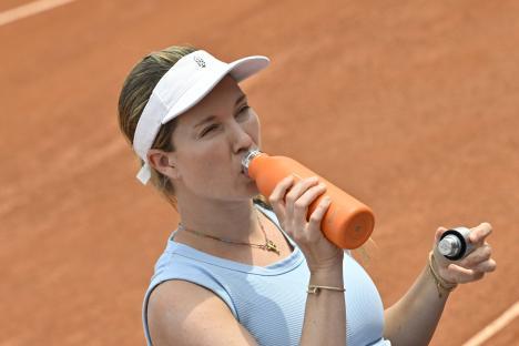 Danielle Collins drinking from a water bottle during a tennis match.