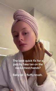 Woman using baby oil and a brush to blend patchy fake tan.