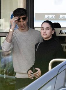 Romeo Beckham and a woman arriving at an airport.