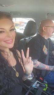 Woman and man in a car; woman giving peace sign.