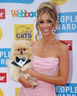 Laura Anderson holding her Pomeranian dog in a tuxedo bow tie.