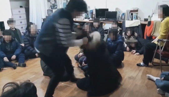 A person assaulting another person while surrounded by a group of people.