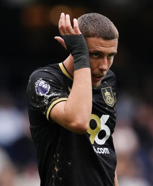 Burnley's Maxime Esteve in a black and gold uniform with a wrapped wrist, looking towards the right side of the frame.