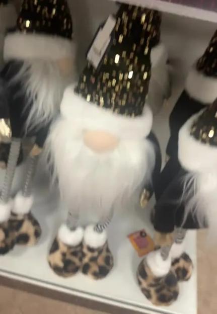 Several gnome figurines with black and gold sequined hats, white beards, and leopard print shoes on a shelf.