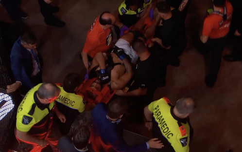 Paramedics carrying an injured fighter on a stretcher.