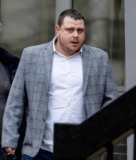 Man in a gray jacket at a trial.