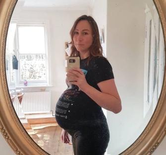 Pregnant woman taking a selfie in a mirror.