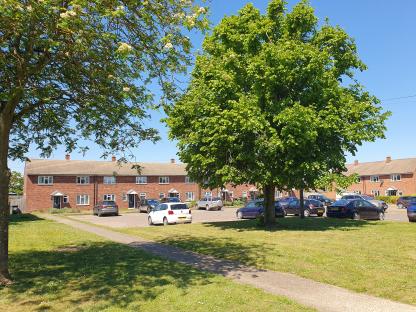 General view of Elm Road, Marham, with cars parked in front of houses.
