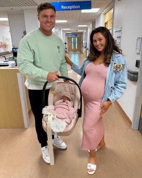 Parents holding their newborn baby in a car seat.