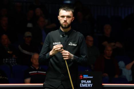 Dylan Emery chalking his cue during a snooker match.