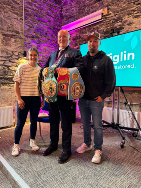 Three people posing with boxing championship belts.
