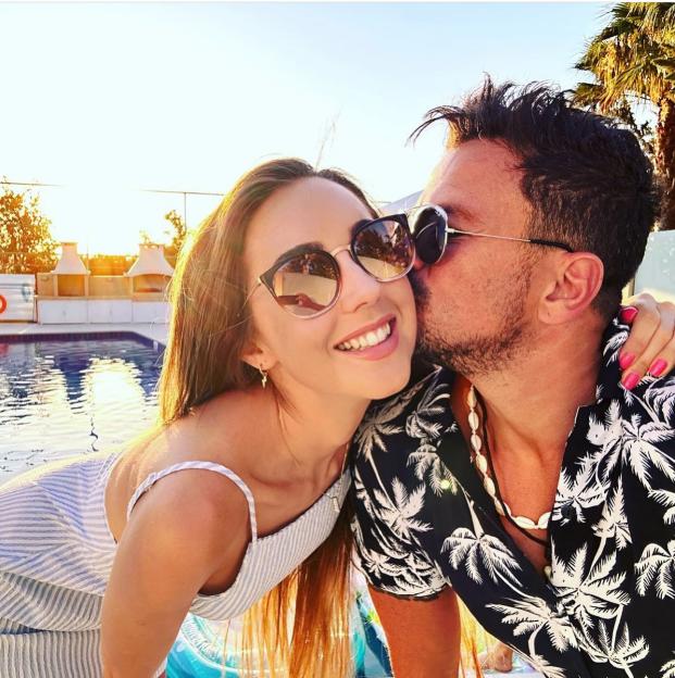 Couple kissing by a pool.