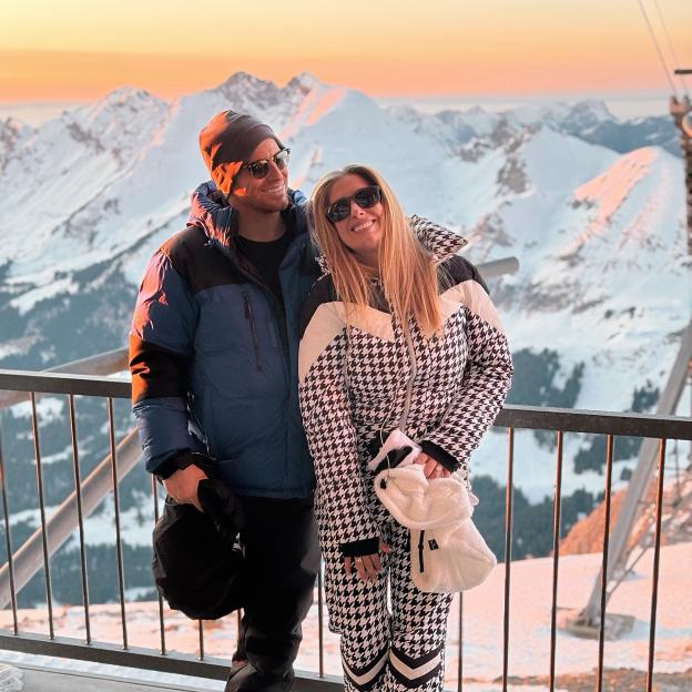 Couple posing on mountain overlook at sunset.