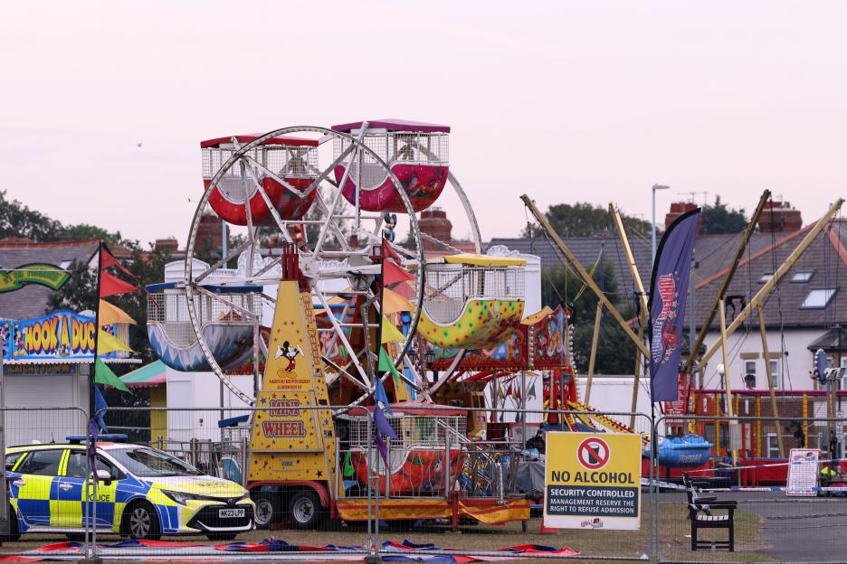 Police car and cordon around a fairground ride.