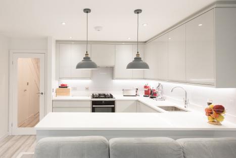 Modern kitchen with gray cabinets and white countertops.