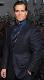 Henry Cavill in a dark suit and tie.