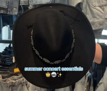 Black cowboy hat with silver chain detail among denim jackets.