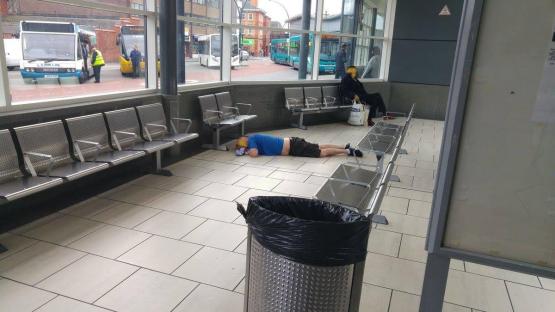 Man lying on the floor of a bus station.