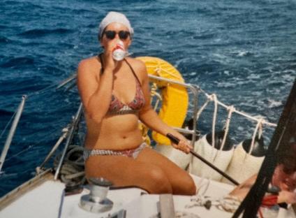 Woman in bikini drinking from a can while sailing.